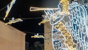 A street scene with illuminated decorations, a café with outdoor seating, and parked cars. - Dimora Rhea (Salerno)