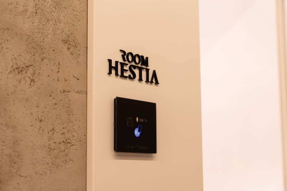 Ein an der Wand befestigtes Schild mit der Aufschrift "ROOM HESTIA" und einem digitalen Schloss, das einen sicheren Raum anzeigt.