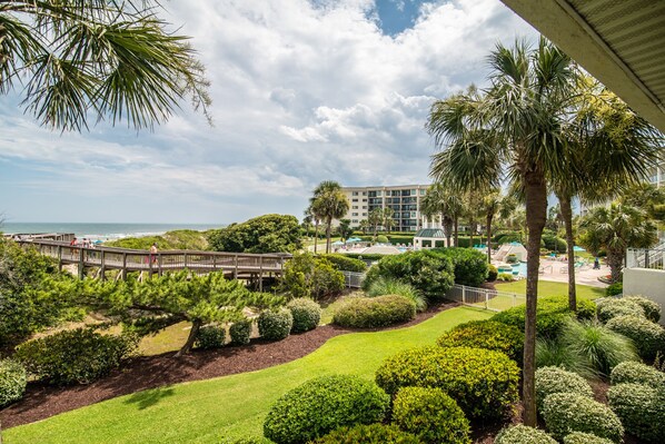 A resort with a view of the ocean, palm trees, and a bridge.