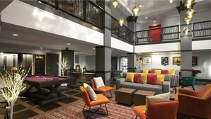 A spacious lobby with a pool table, comfortable seating, and a staircase connecting two floors.