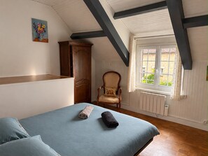 Une chambre à coucher avec un lit, une chaise, une fenêtre et un tableau accroché au mur.