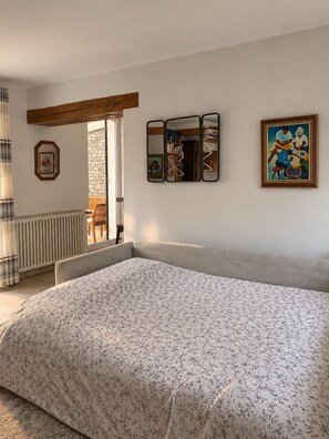 Une chambre à coucher avec un lit, un radiateur, une fenêtre avec des rideaux et un tableau accroché au mur.