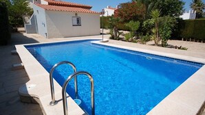 Ein rechteckiger Pool mit gefliestem Sonnendeck und Metallgeländern.