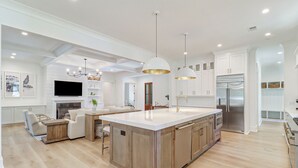 A modern kitchen with a central island, white cabinetry, and stainless steel appliances.