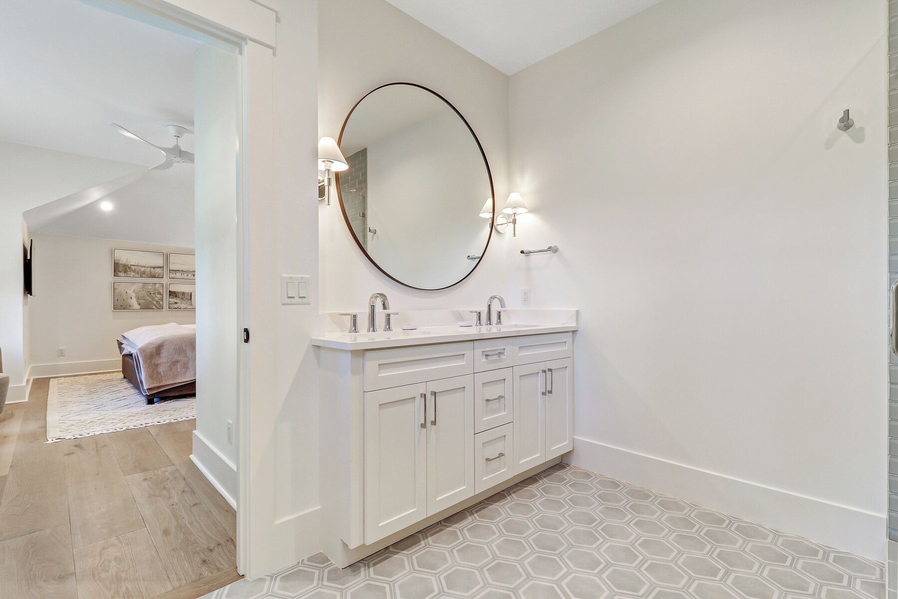 Un bagno moderno con un mobile lavabo bianco, uno specchio grande e un pavimento in piastrelle esagonali.