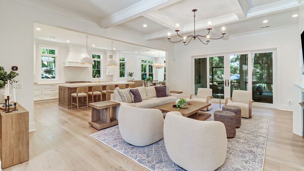 A spacious living room with a large sofa, a coffee table, and a dining area with wooden chairs.