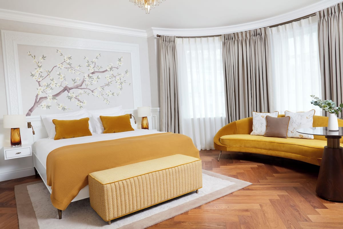 Une chambre moderne avec un grand lit, un canapé, une petite table et un élément décoratif mural.