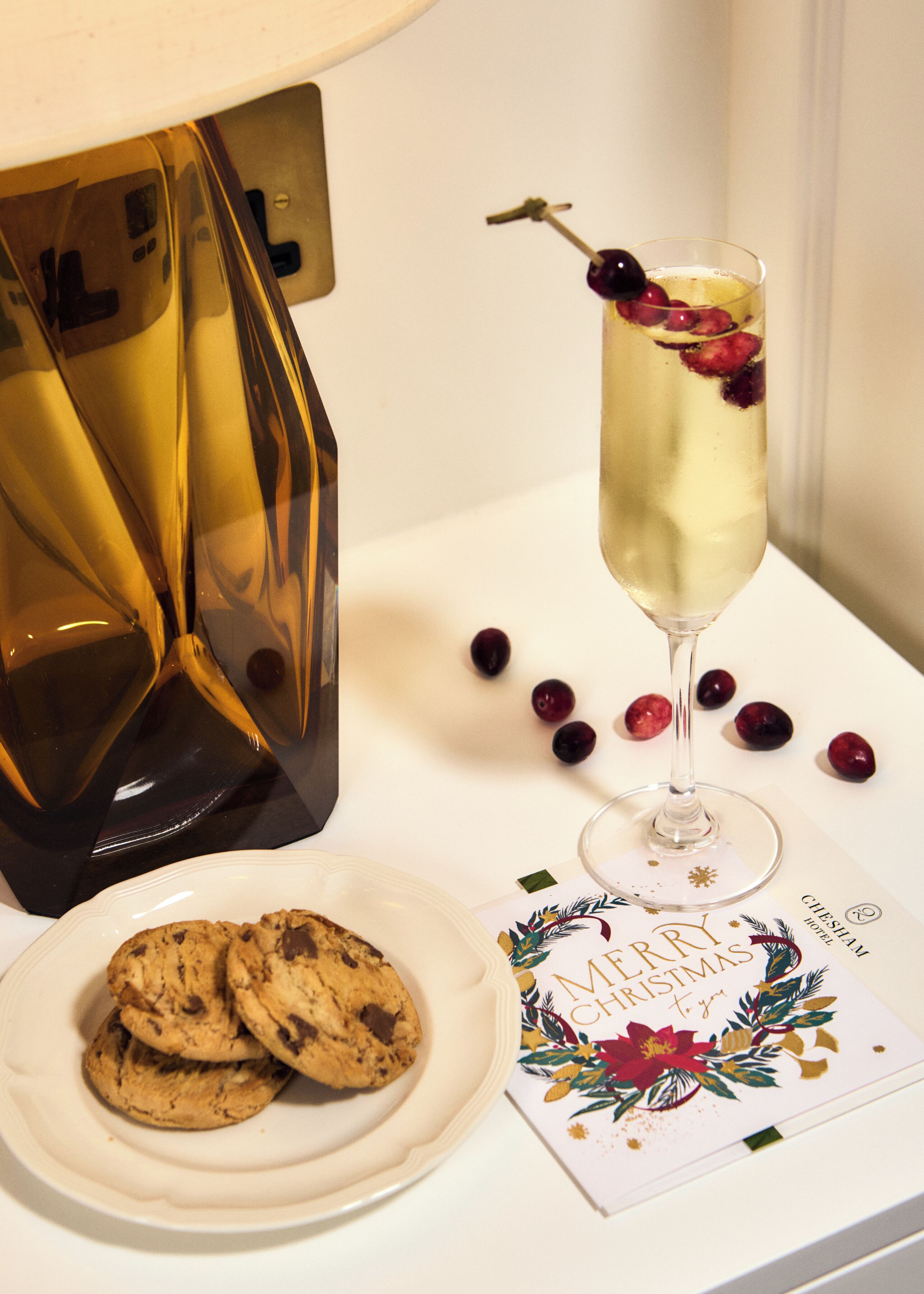 A table with a glass of champagne, a plate of cookies, and a Christmas card.