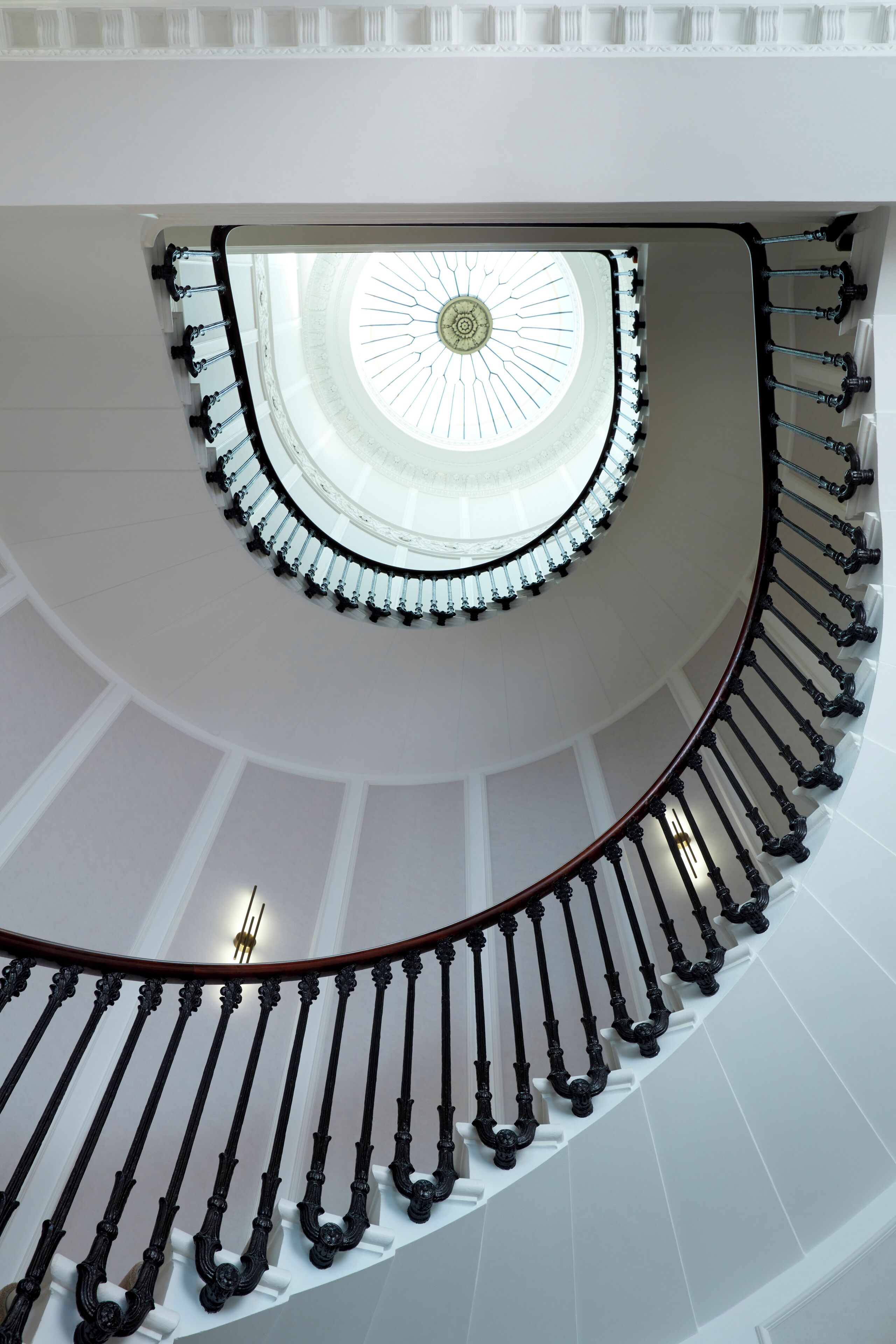 A grand spiral staircase with a central skylight and ornate balustrades.