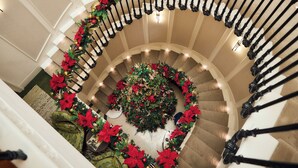 A grand spiral staircase with a Christmas tree at the center, surrounded by festive decorations. - 2 Chesham Hotel (London)