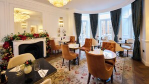A luxurious dining room with a grand chandelier, elegant chairs, a fireplace with festive decorations, and large windows with curtains. - 2 Chesham Hotel (London)