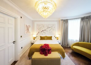 A hotel room with a large bed, a chandelier, a yellow armchair, and a window with curtains. - 2 Chesham Hotel (London)