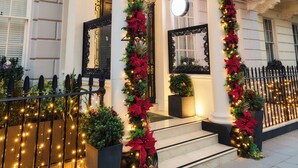 A building entrance with a white facade, columns, and a balcony with string lights. - 2 Chesham Hotel (London)