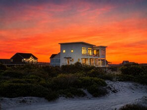 Une maison à deux étages située en bord de mer, dotée d’un balcon et offrant une vue sur l’océan.