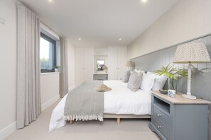 Une chambre à coucher avec un lit, une table de chevet, une lampe et une vue sur la salle de bain.