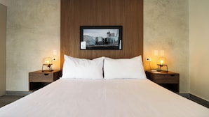 A hotel room with a large bed, two bedside tables with lamps, and a framed cityscape picture on the wall. - Caster by Wynwood House (Lima)
