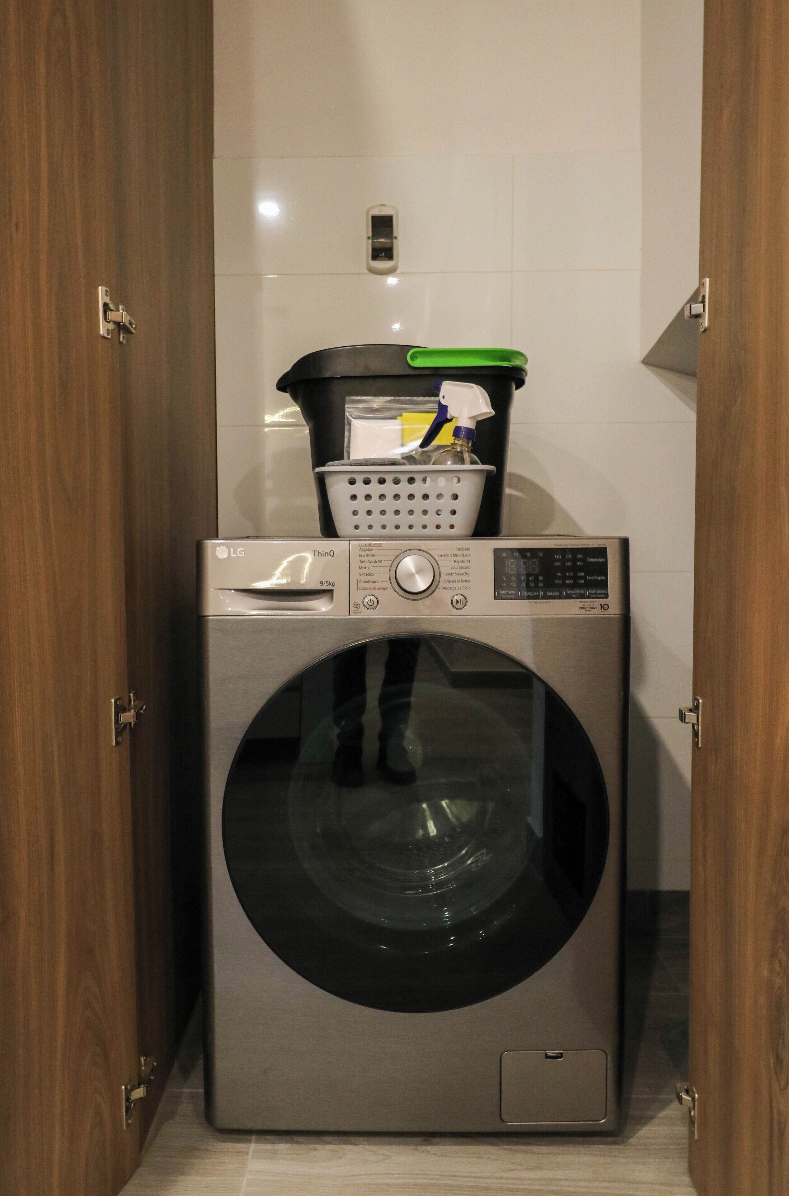 Lavadora de carga frontal compacta, con panel de control y una cesta superior de acero inoxidable.