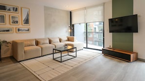 A modern living room with a sofa, coffee table, and a flat-screen TV mounted on a green wall. - Caster by Wynwood House (Lima)