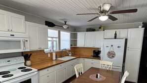 A kitchen with white cabinets, a wooden countertop, a dining table with chairs, a stove, a refrigerator, and a ceiling fan. - Amazing views, great fishing and huge dock make this the perfect PK get-away. (Graham)
