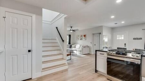Uma cozinha espaçosa com fogão moderno, área de refeições com mesa e cadeiras brancas, e escada que leva a outro andar.