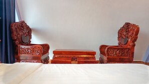 A bed with a white sheet, flanked by two intricately carved wooden nightstands. - I AM Koh Ker (Kuleaen)