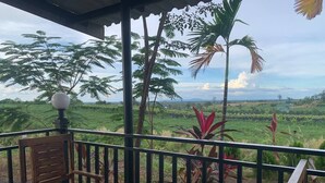 A wooden chair and table on a balcony with a view of a green landscape and palm trees. - I AM Koh Ker (Kuleaen)