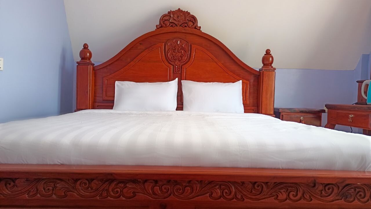 A neatly made bed with a wooden headboard and two pillows.