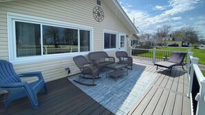 A deck with outdoor furniture, a large window, and a view of the neighborhood. - Cozy cottage with lake view! 20 min from Cedar Point, Kalahari, & Sports Force! (Vermilion)