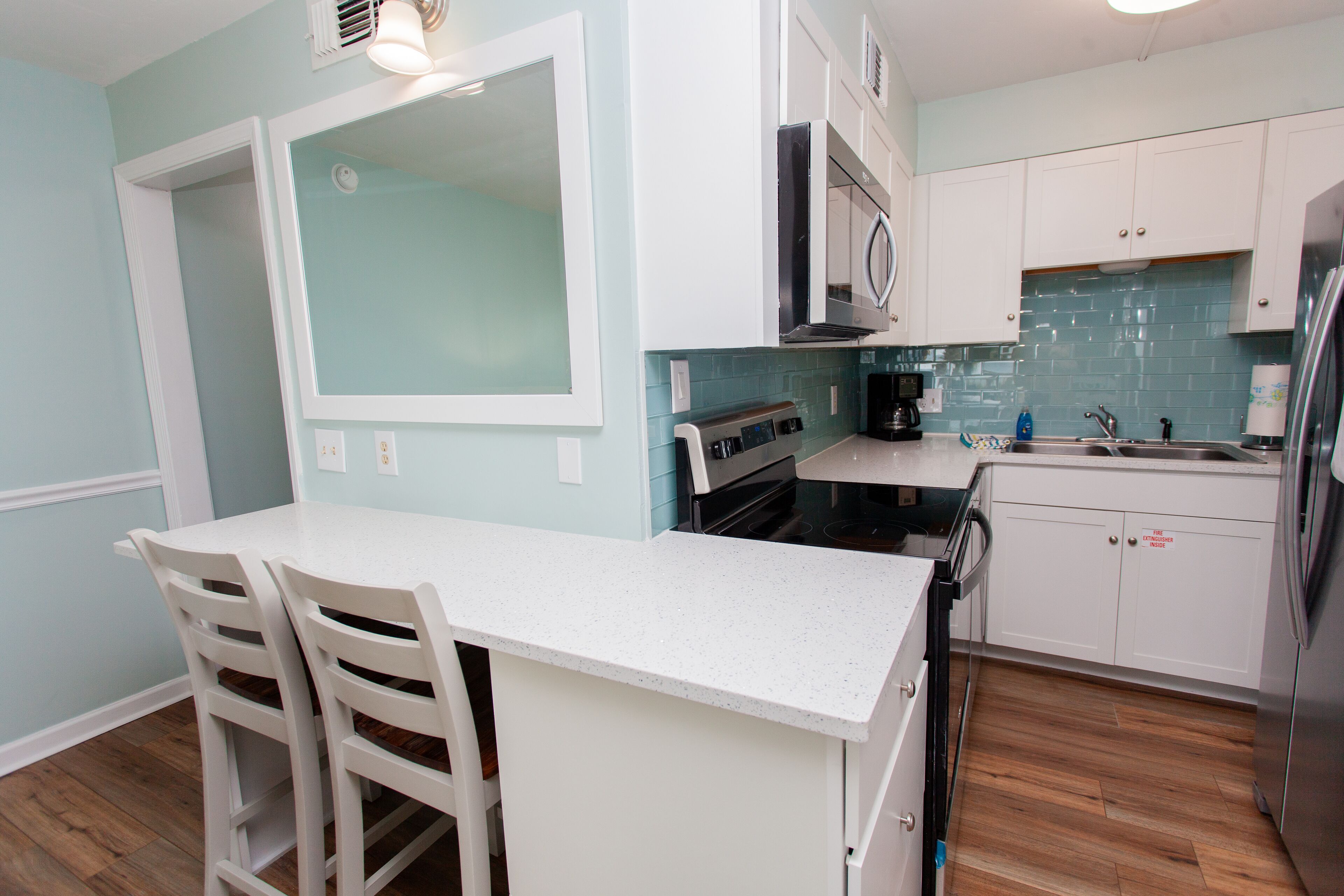 A kitchen with white cabinets, a stainless steel refrigerator, and a microwave.