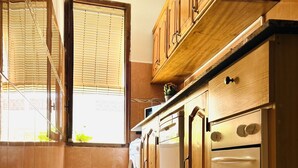 A kitchen with wooden cabinets, a washing machine, and an oven. - La Caracola (Benicarlo)
