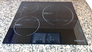 A black induction cooktop with a digital control panel and a Corbero logo. - La Caracola (Benicarlo)