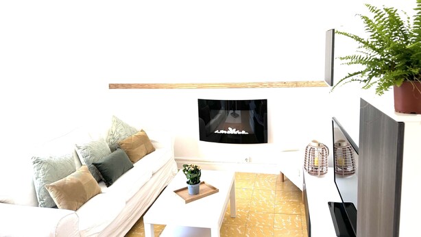 A modern living room with a white sofa, a coffee table, a flat-screen TV, and a potted plant. - La Caracola (Benicarlo)