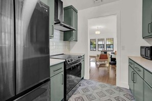 A kitchen with stainless steel appliances, green cabinets, and a patterned floor.