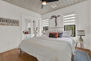 A bedroom with a large bed, a ceiling fan, a wall-mounted tree sculpture, and a sign with historical information.