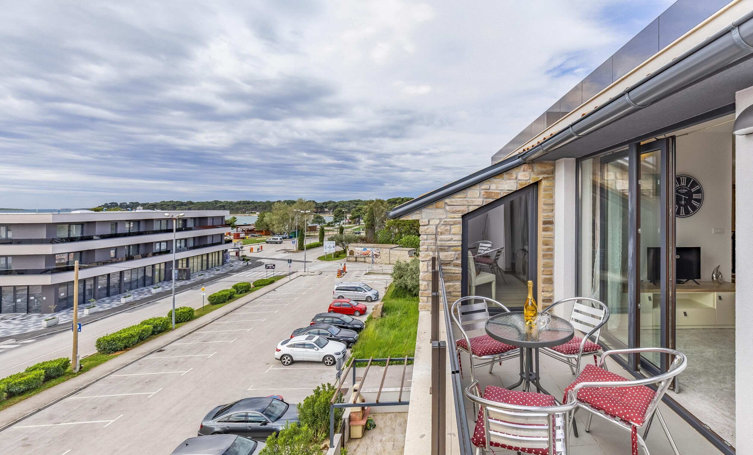 A balcony with outdoor seating and a view of a parking lot and buildings.