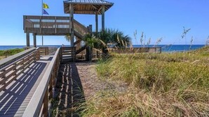A wooden pier leading to a gazebo with a clear view of the ocean.