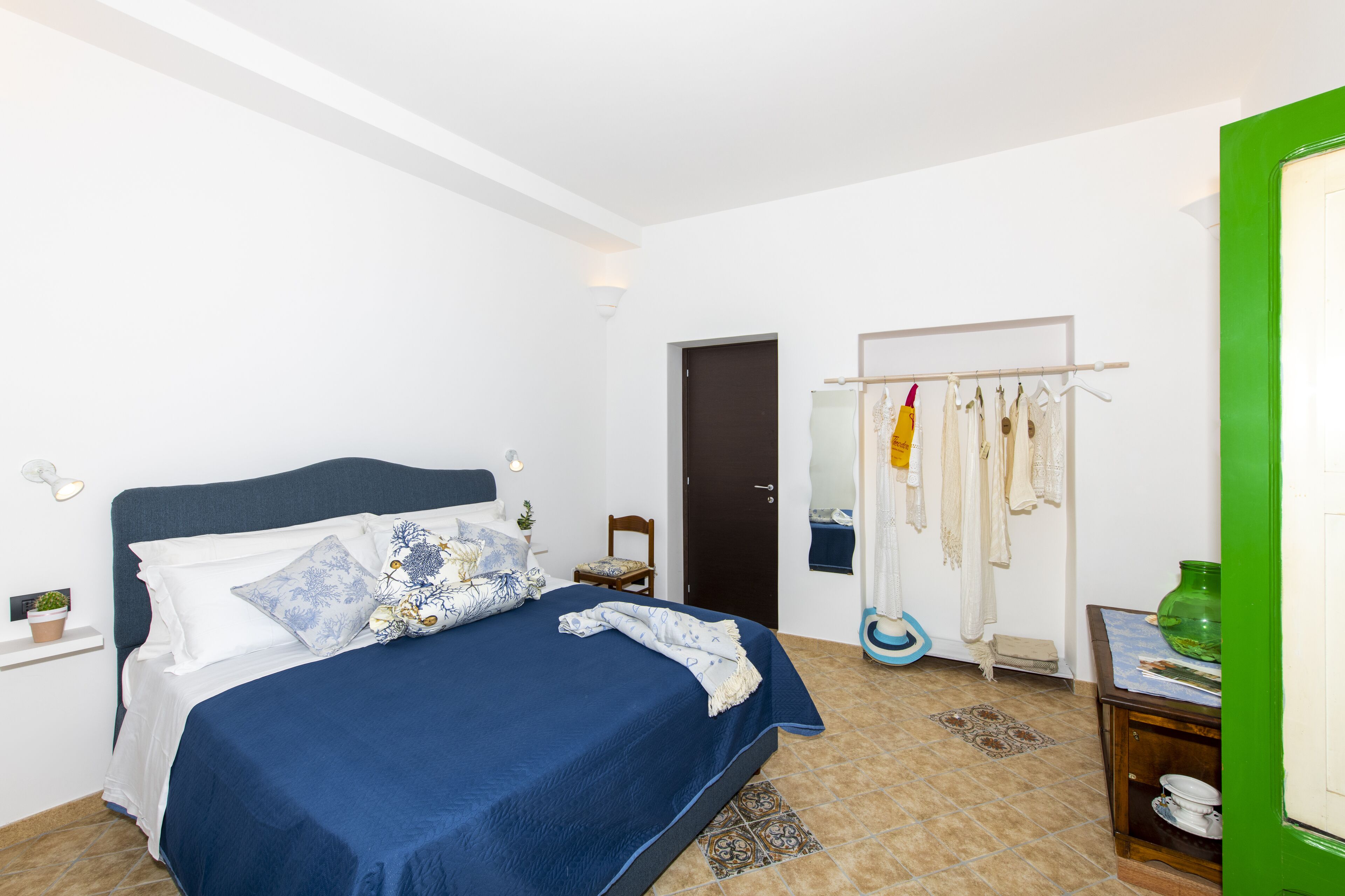A bedroom with a bed, a wardrobe, a mirror, and a green door.