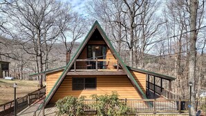Une cabane avec une façade en bois, un balcon et une terrasse.