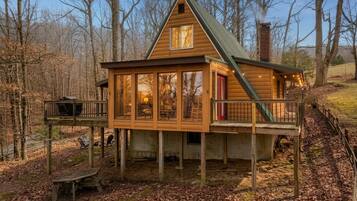 A wooden cabin with a balcony, large windows, and a chimney.