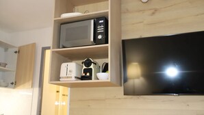 A kitchen with a microwave, toaster, and a flat-screen TV mounted on the wall. - Floridianes Provence (Aix-en-Provence)