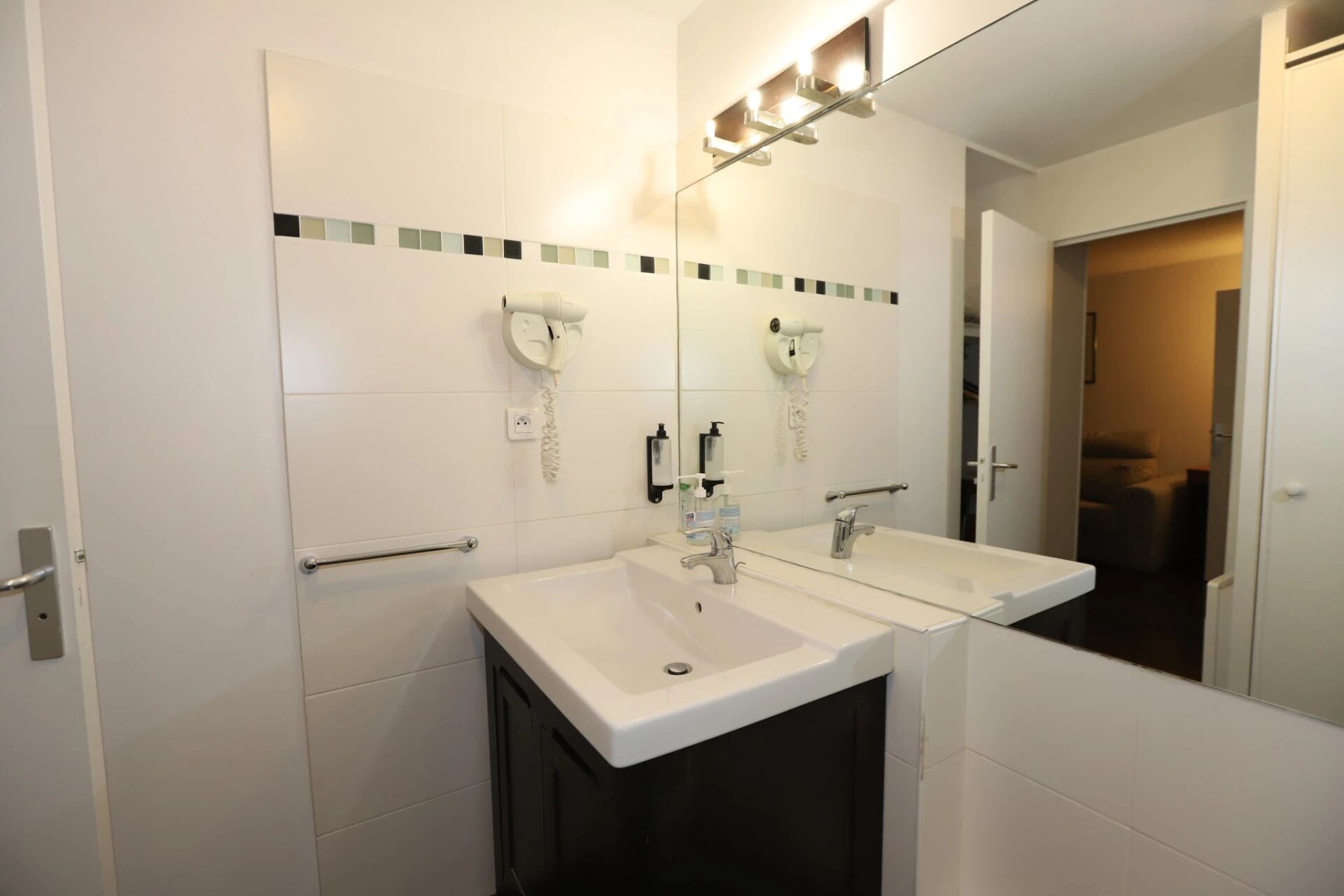 Un baño moderno con dos lavamanos, un espejo y un secador de pelo.