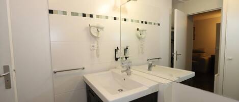 Un baño moderno con dos lavamanos, un espejo y un secador de pelo.