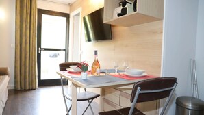 A compact dining area with a table set for two, a bottle of wine, and a television mounted on the wall. - Floridianes Provence (Aix-en-Provence)