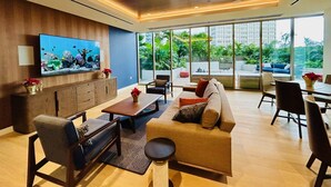 A modern living room with a large TV, wooden cabinets, a sofa, and a dining area.