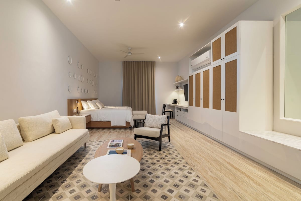 Een moderne hotelkamer met een bed, een bank en een eethoek.
