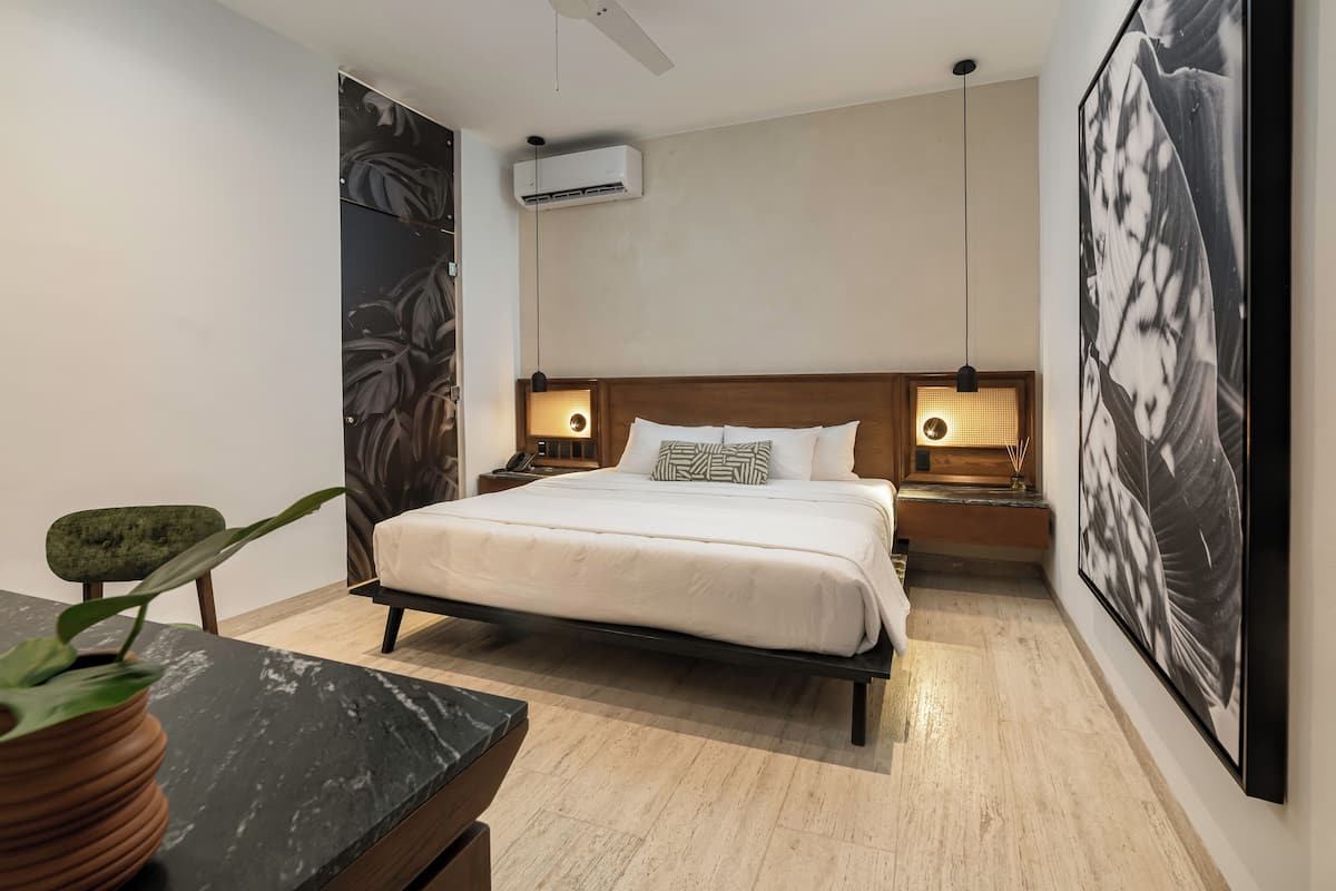 Een moderne slaapkamer met een bed, bedlampjes, een airconditioning en een groot gepresenteerd schilderij aan de muur.