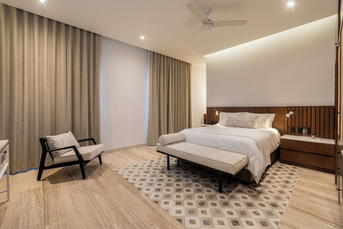 Een moderne hotelkamer met een groot bed, een stoel, een bureau en een plafondventilator.