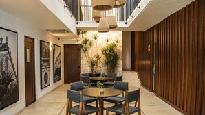 Un hall d’hôtel moderne avec une table de salle à manger ronde, des chaises bleues à revêtement en tissu et un mur décoratif en bois.