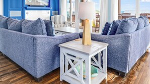 Ein Wohnzimmer mit einem blauen Sofa, einem weißen Tisch und einem Deckenventilator.