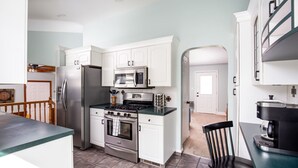 A modern kitchen with white cabinetry, stainless steel appliances, and a teal countertop.
